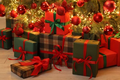 Many gift boxes under decorated Christmas tree indoors