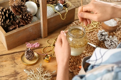 Photo of Woman making snow globe at wooden table, closeup