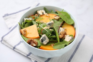 Tasty salad with persimmon, blue cheese and walnuts served on white table