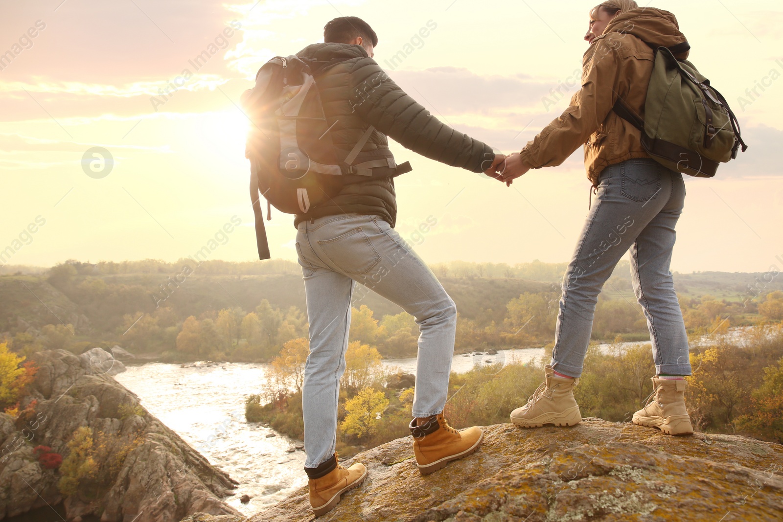 Photo of Couple of hikers with travel backpacks enjoying beautiful view near mountain river