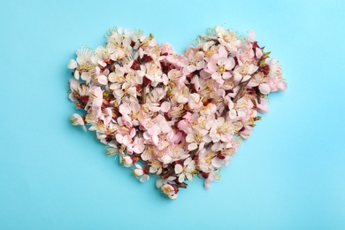 Heart made of beautiful fresh flowers on color background, flat lay. Spring blossom