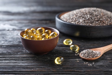 Spoon of chia seeds and capsules with oil on table, closeup. Space for text