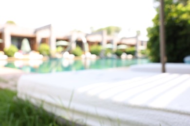 Photo of Sun loungers near outdoor swimming pool, blurred view. Luxury resort