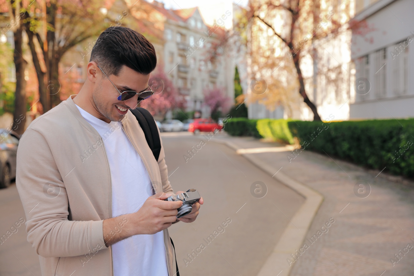 Photo of Happy male tourist with camera on city street