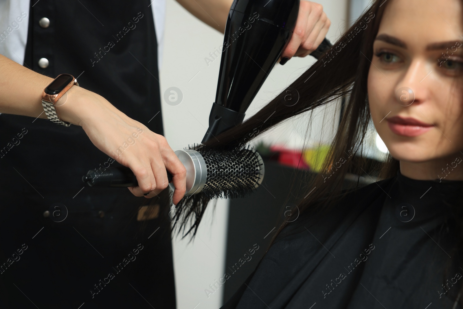 Photo of Hairdresser drying woman's hair in beauty salon