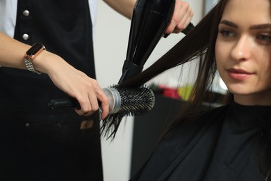 Hairdresser drying woman's hair in beauty salon