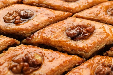 Photo of Delicious honey baklava with walnuts as background, closeup