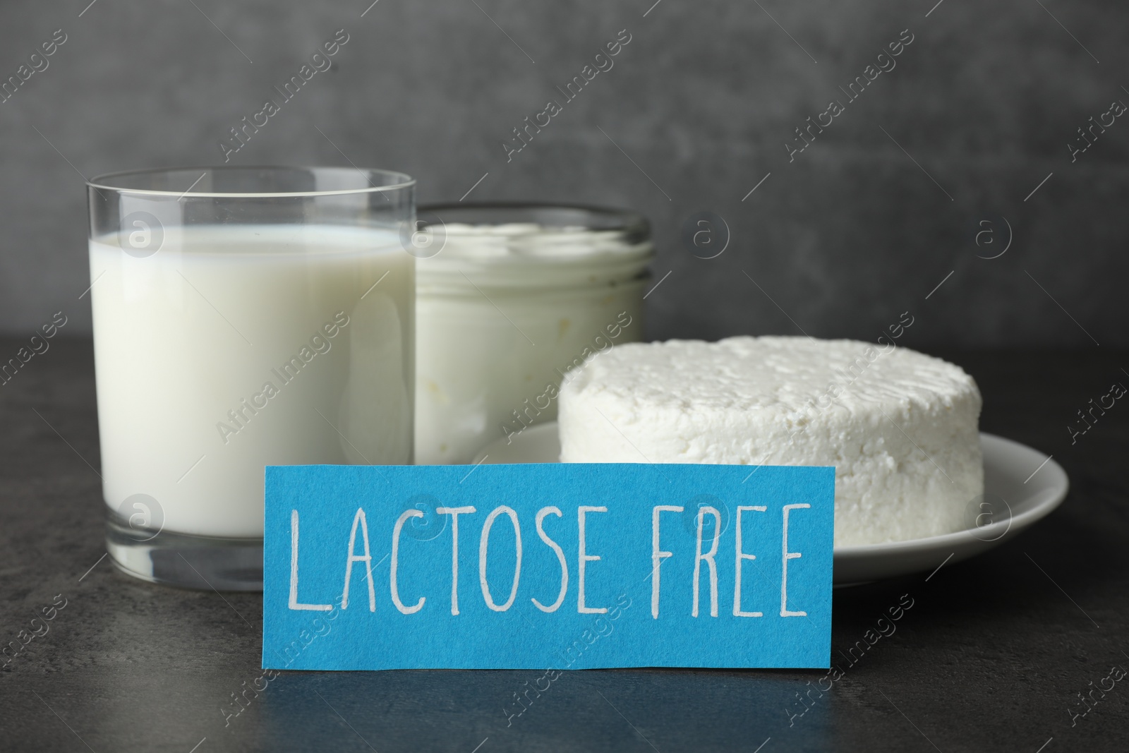 Photo of Card with phrase Lactose free and different fresh products on grey table