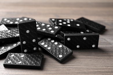 Photo of Black domino tiles on wooden table, closeup