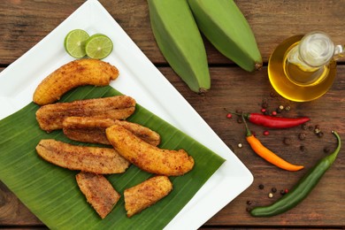 Photo of Delicious fried bananas, fresh fruits and different peppers on wooden table, flat lay