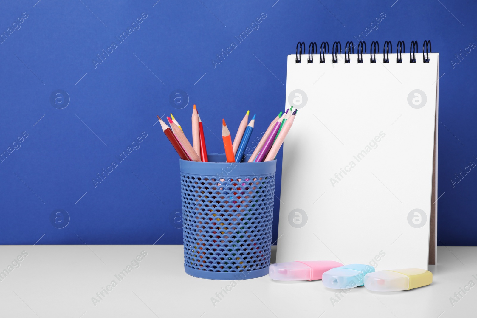 Photo of Different school stationery on white table against blue background, space for text. Back to school