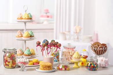 Candy bar with different sweets on white table against blurred background