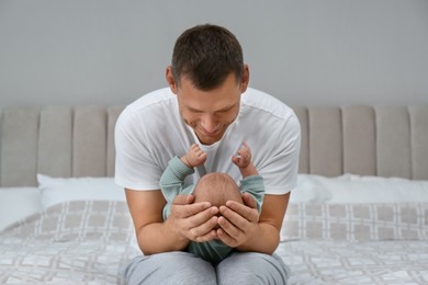 Photo of Happy father holding his cute baby on bed at home