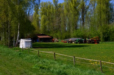 Beautiful countryside with agricultural machinery and solar panels on sunny spring day