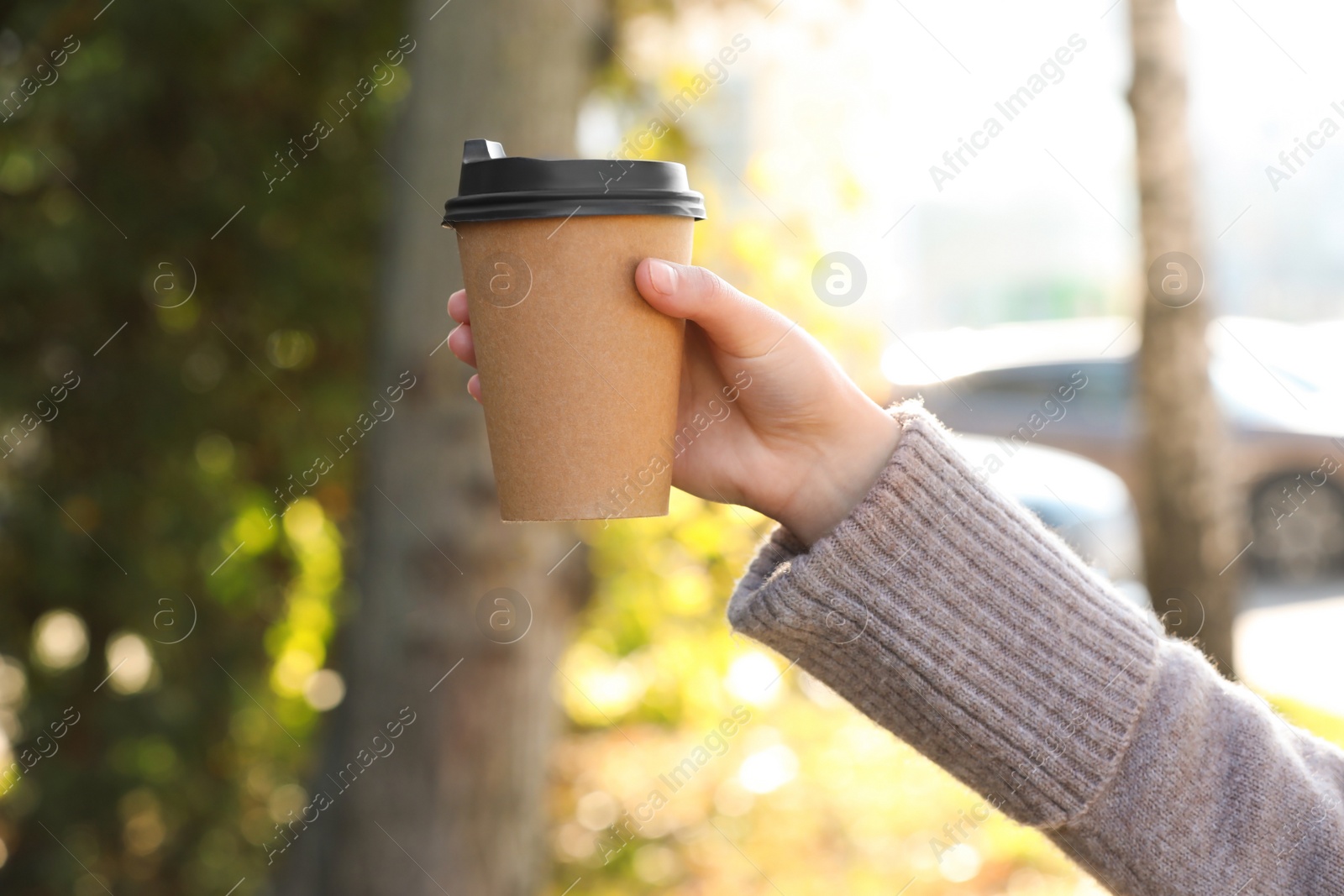 Photo of Coffee to go. Woman holding takeaway cardboard cup on city street, closeup