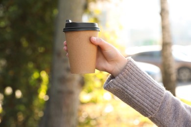 Coffee to go. Woman holding takeaway cardboard cup on city street, closeup