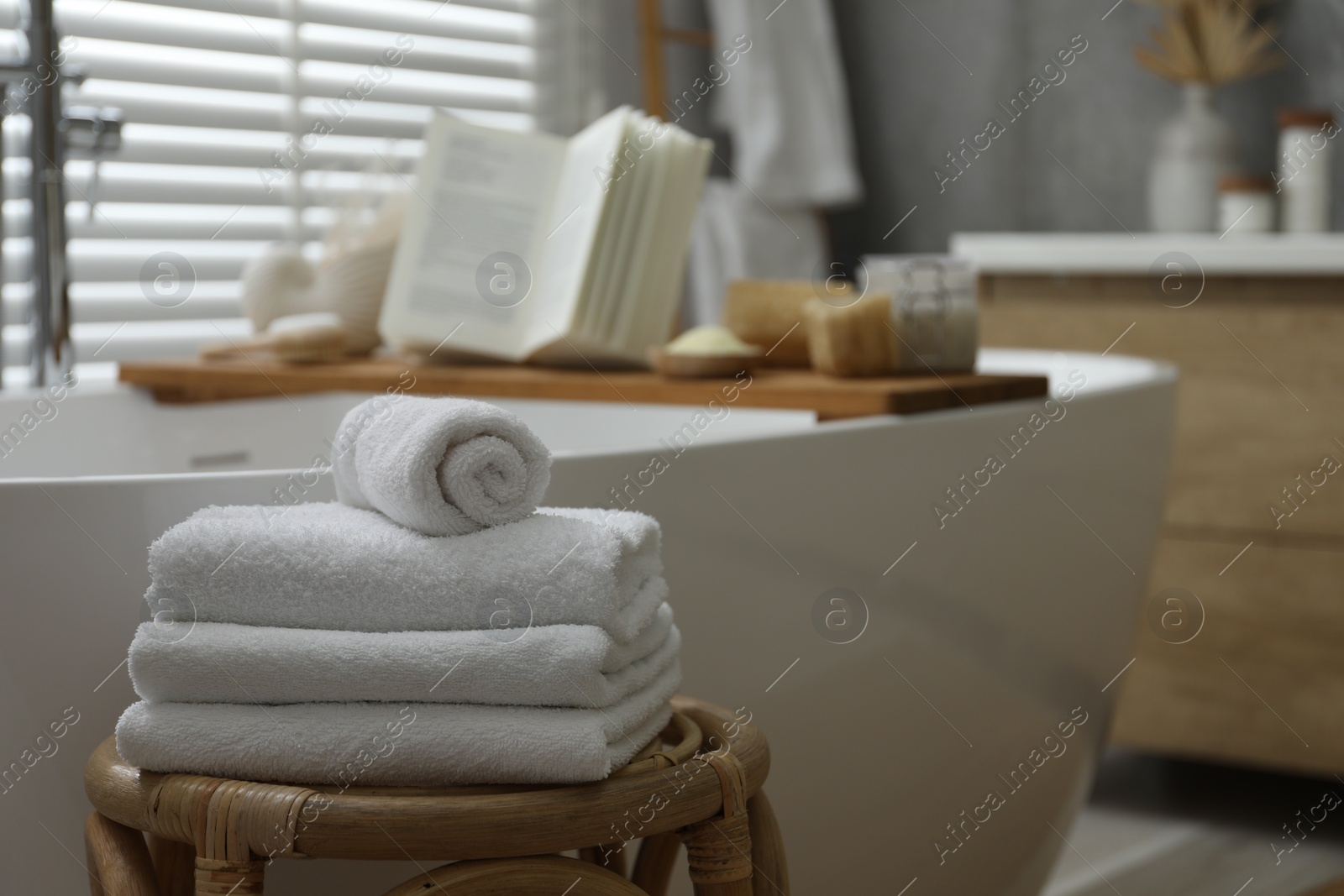 Photo of Wooden tray with spa products and book on bath tub in bathroom, selective focus