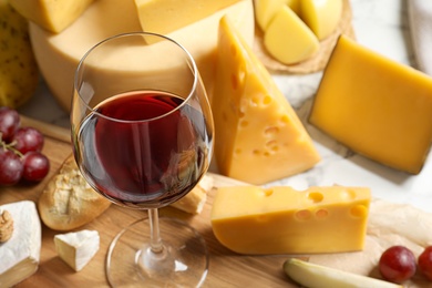 Photo of Glass of wine served with delicious cheese and snacks on table, closeup