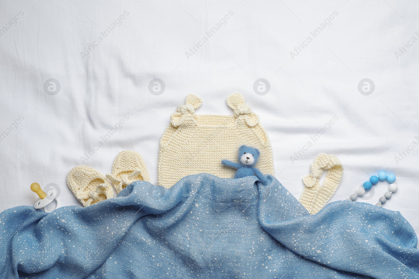 Photo of Flat lay composition with child's clothes and accessories on white fabric, space for text