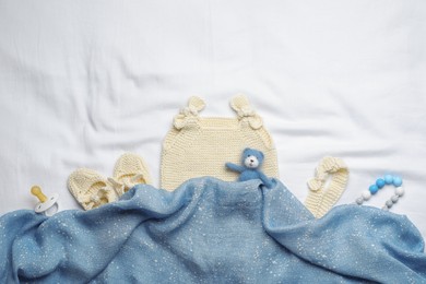 Photo of Flat lay composition with child's clothes and accessories on white fabric, space for text
