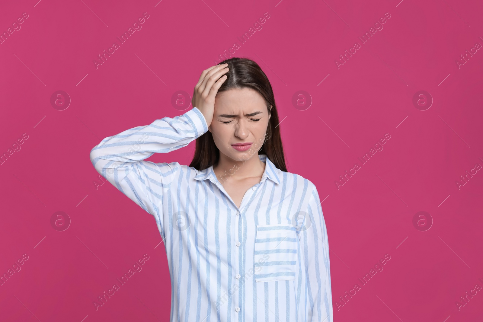 Photo of Young woman suffering from headache on pink background