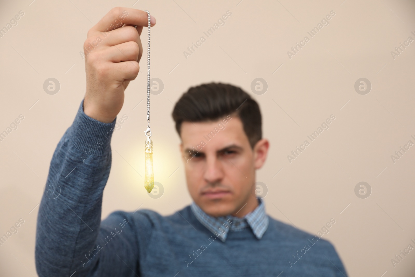 Photo of Psychotherapist with pendulum on beige background. Hypnotherapy session