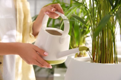 Photo of Woman watering house plant near window indoors, closeup