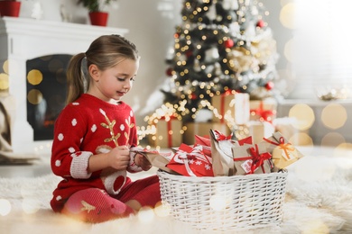 Cute little girl taking gift from Christmas advent calendar at home. Bokeh effect