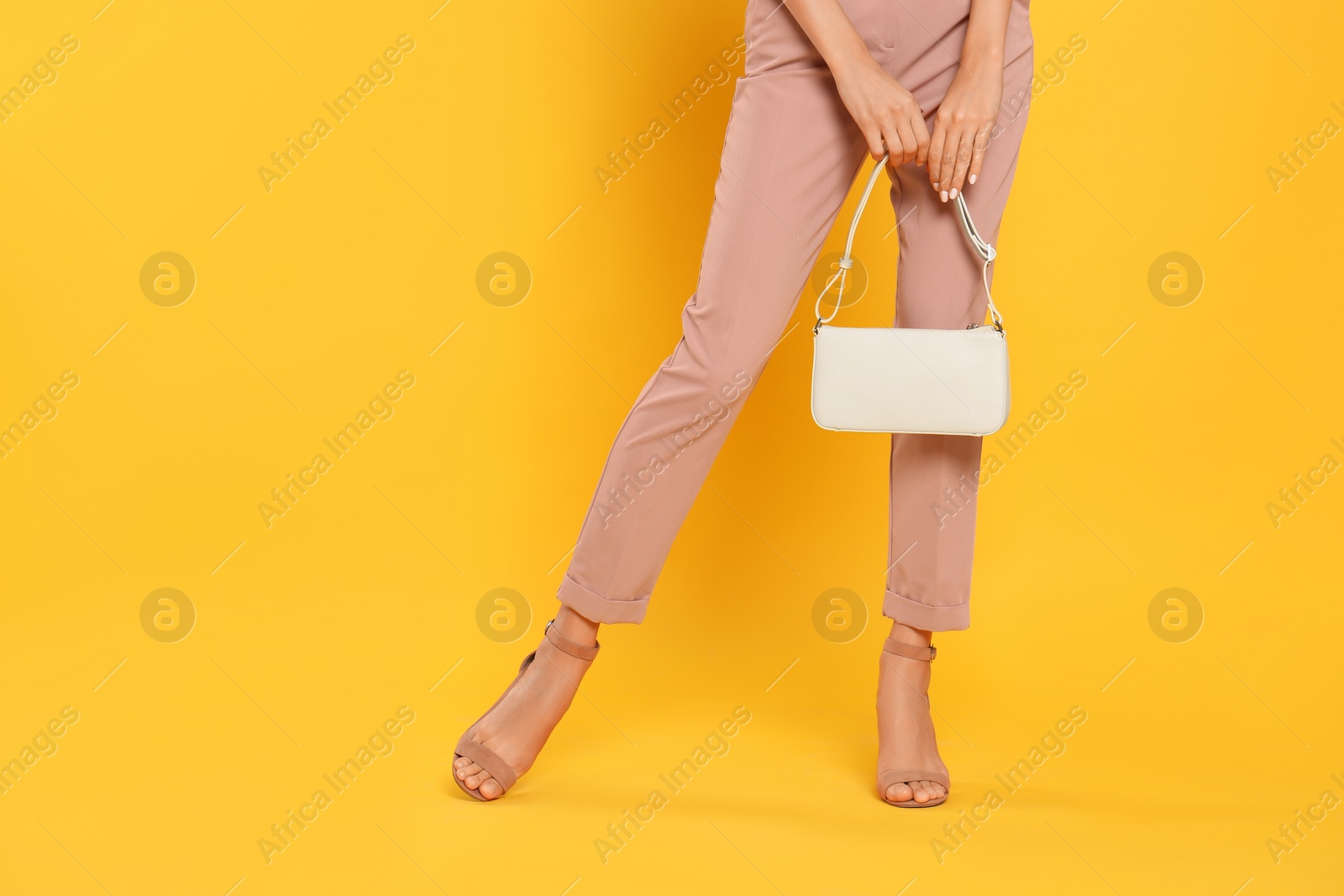 Photo of Woman with stylish bag on yellow background, closeup. Space for text