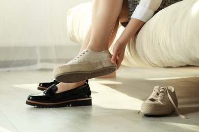 Woman taking off uncomfortable shoes and putting on sneakers in office, closeup