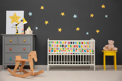 Photo of Cute baby room interior with modern crib and rocking horse