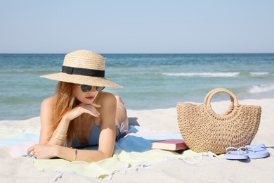 Photo of Beautiful woman with bag and other beach stuff on sand near sea