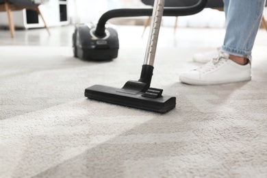 Janitor hoovering carpet with vacuum cleaner indoors, closeup