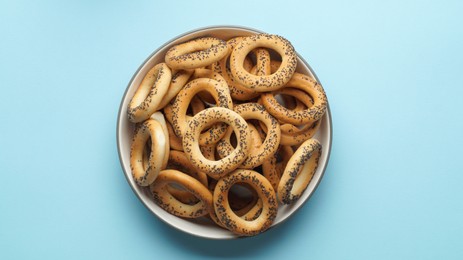 Photo of Bowl with delicious ring shaped Sushki (dry bagels) on light blue background, top view