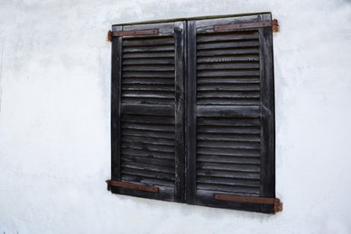 Window with old wooden shutters on concrete wall
