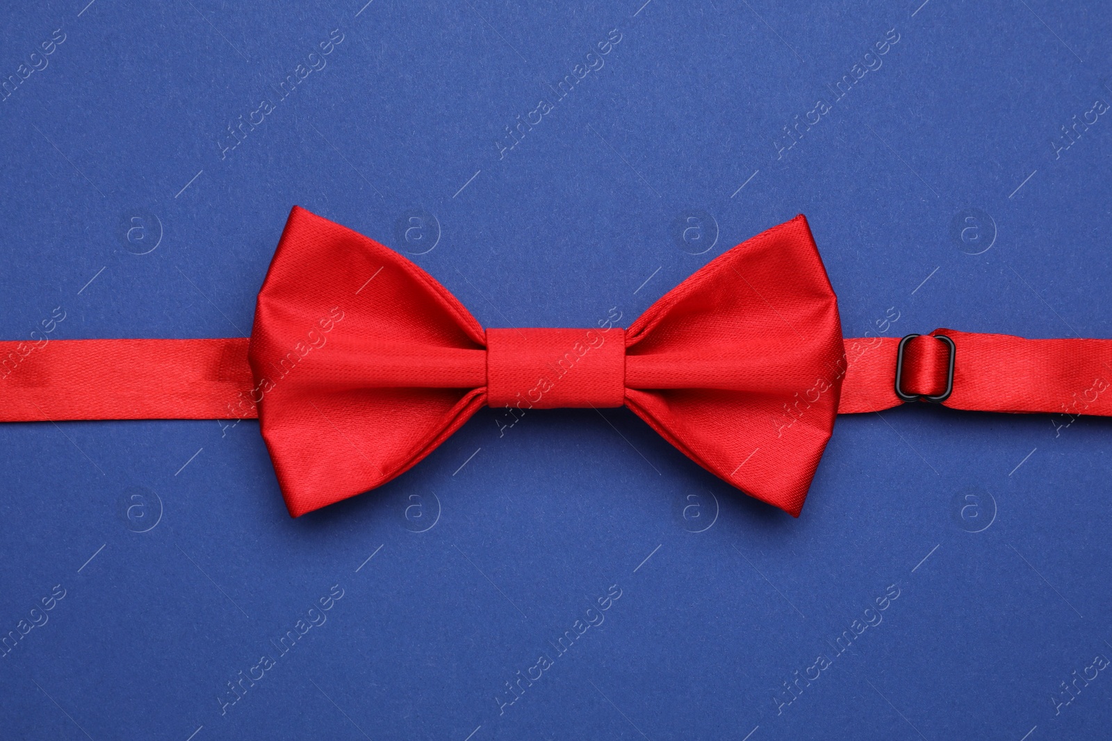 Photo of Stylish red bow tie on blue background, top view