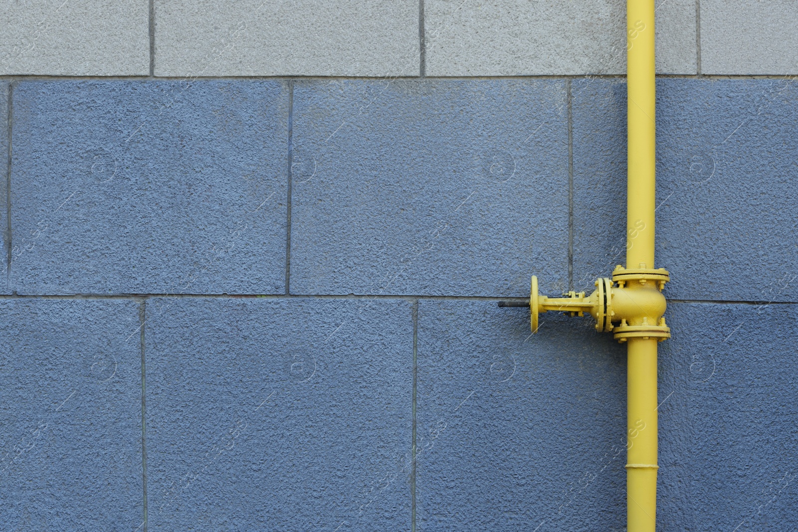 Photo of Yellow gas pipe on grey wall outdoors