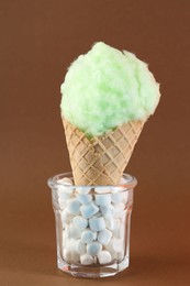 Sweet cotton candy in waffle cone on brown background, closeup