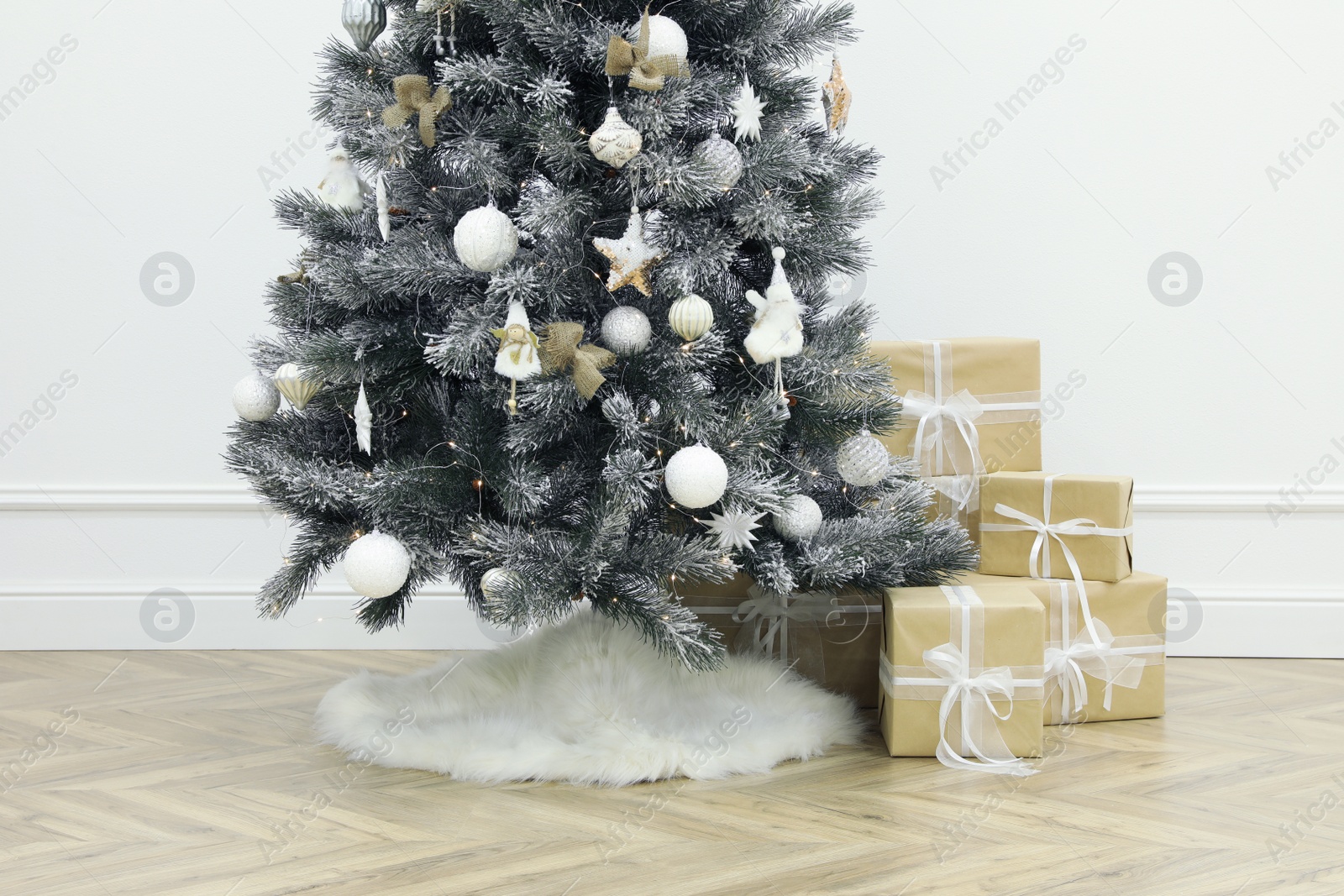 Photo of Beautiful decorated Christmas tree with skirt and gift boxes in room