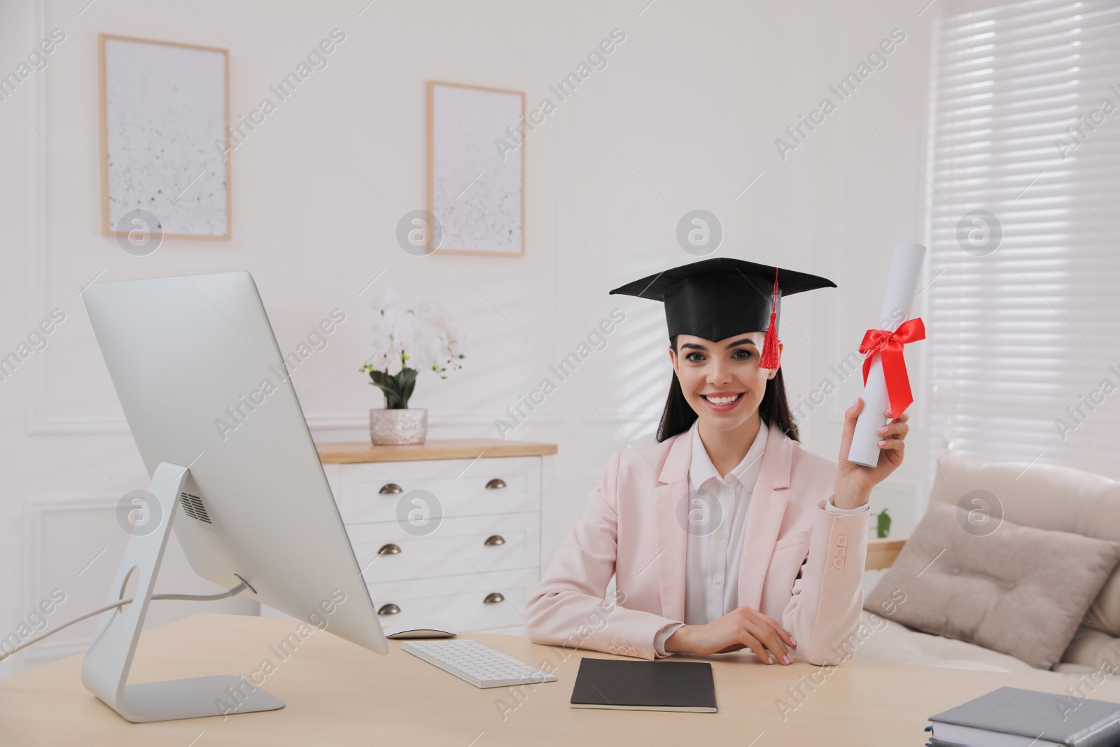 Photo of Happy student with graduation hat and diploma at workplace in office