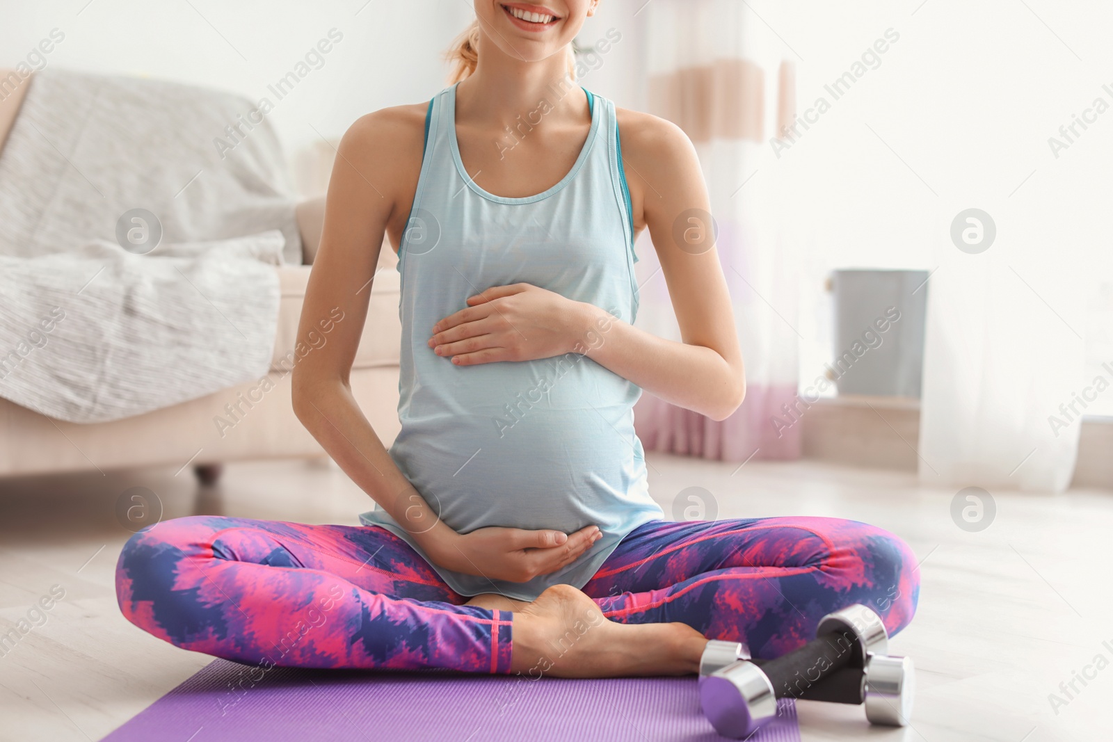 Photo of Young pregnant woman doing exercises at home