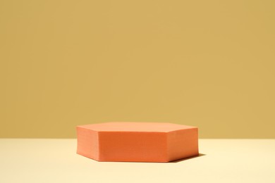 Photo of Orange stand on table against yellow background, space for text. Stylish presentation for product