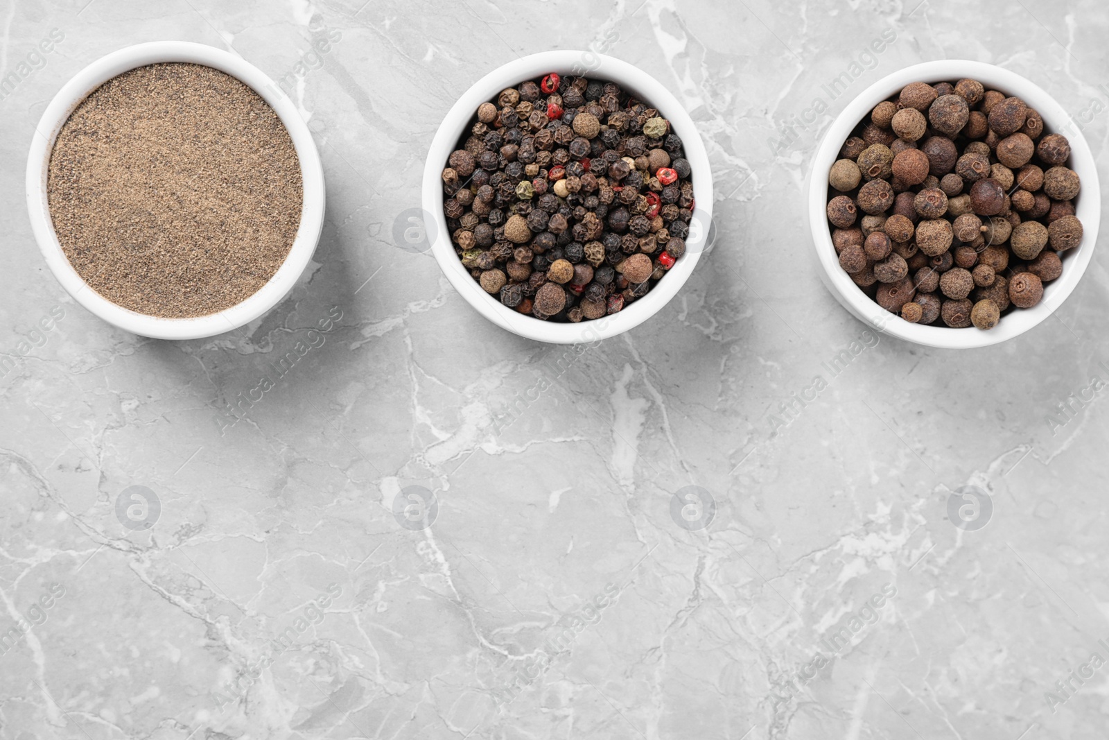 Photo of Ground pepper and corns on grey table, flat lay.  Space for text