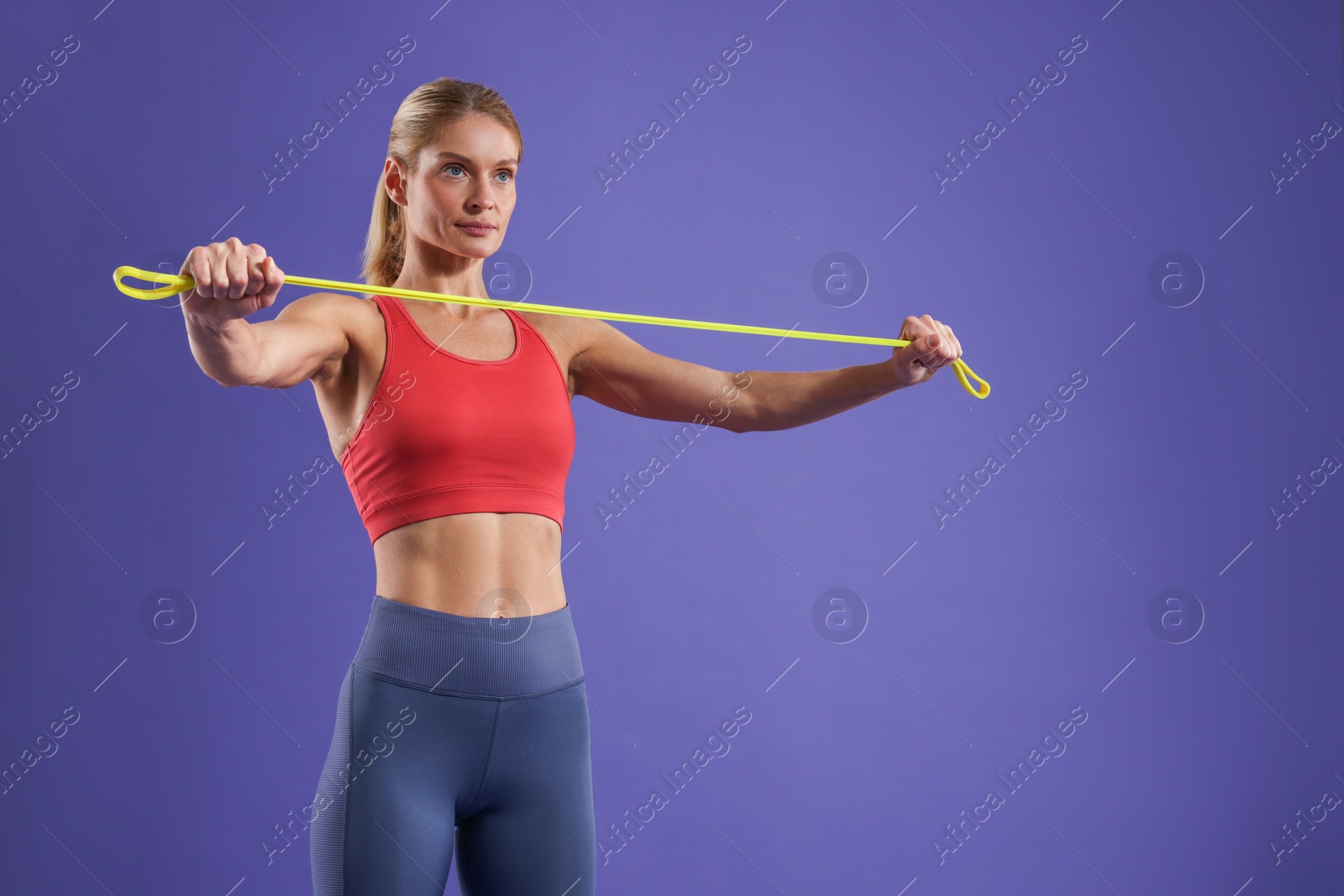 Photo of Athletic woman exercising with elastic resistance band on purple background. Space for text