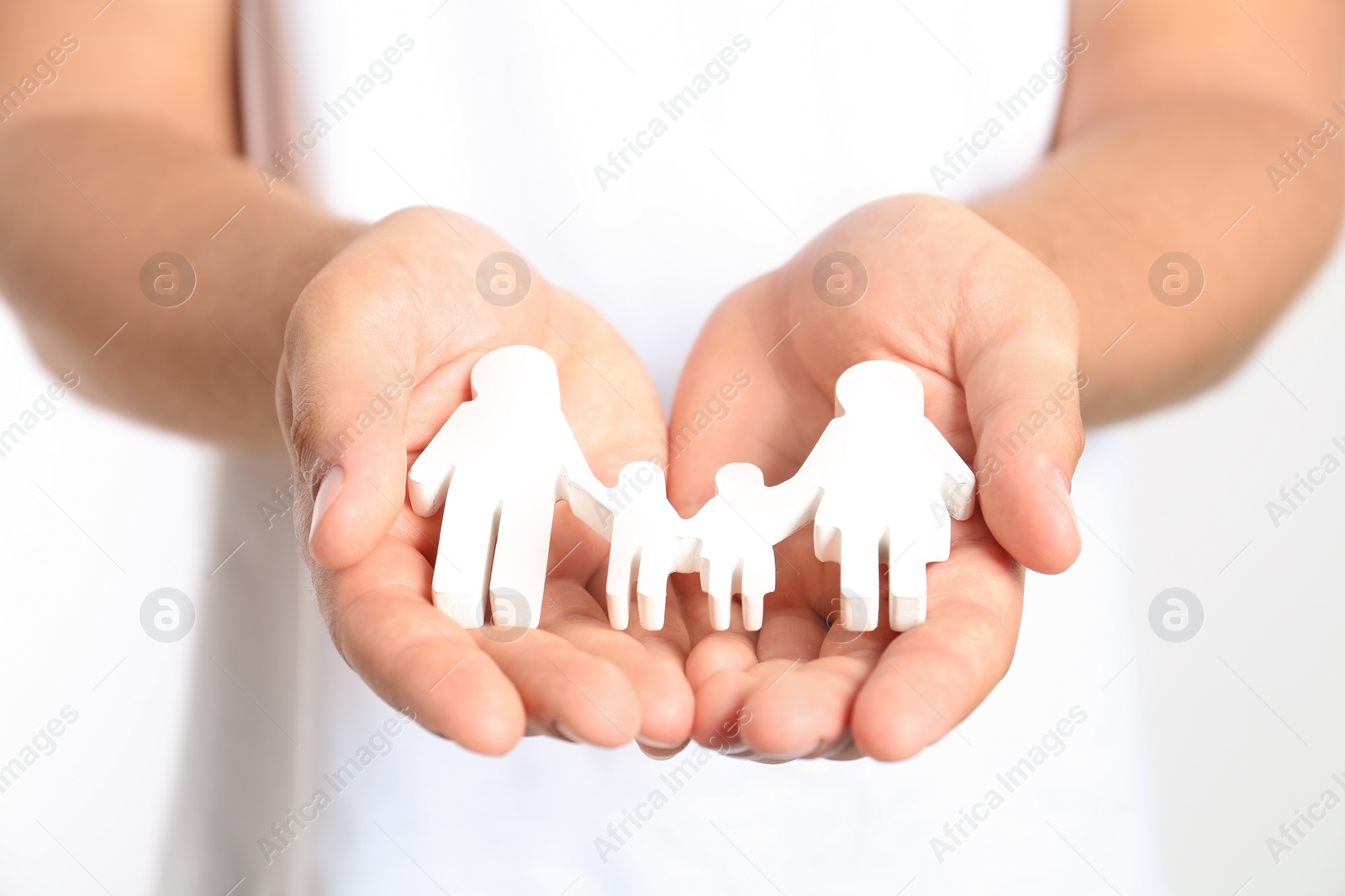Photo of Young man holding wooden family figure on white background, closeup of hands