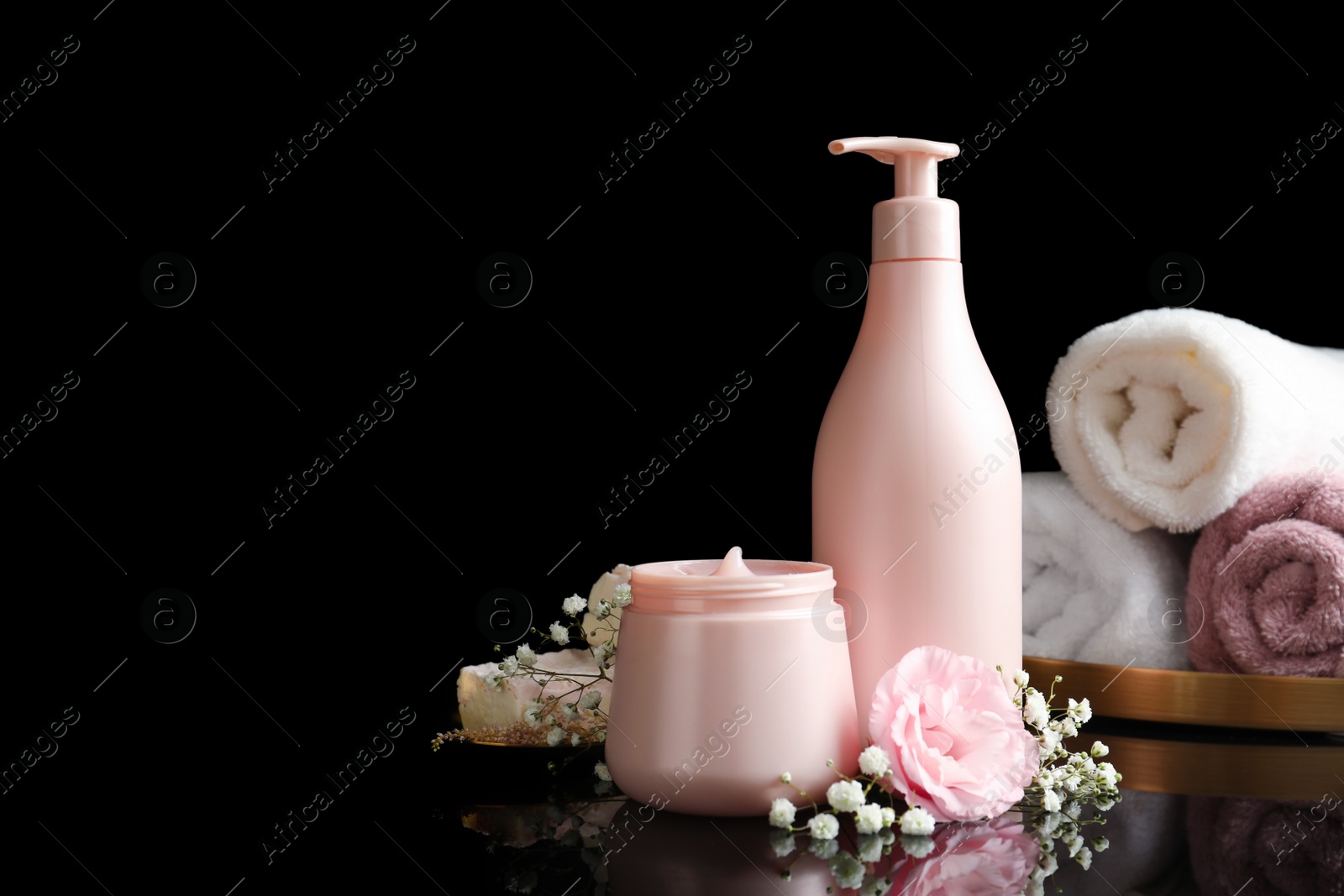 Photo of Hair cosmetic products, towels and flowers on black background. Space for text