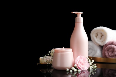 Photo of Hair cosmetic products, towels and flowers on black background. Space for text