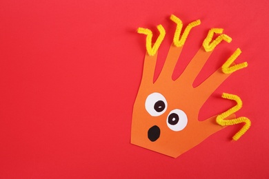 Photo of Funny orange hand shaped monster on red background, top view with space for text. Halloween decoration
