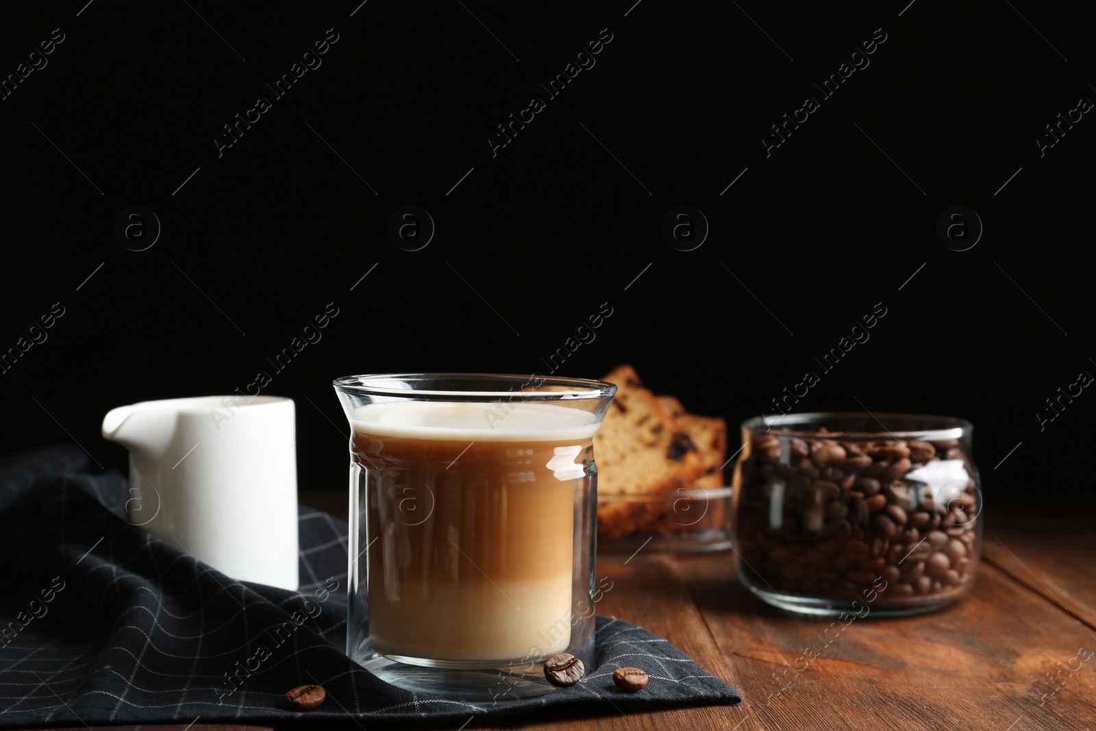 Photo of Composition with glass of delicious coffee drink on wooden table against black background. Space for text