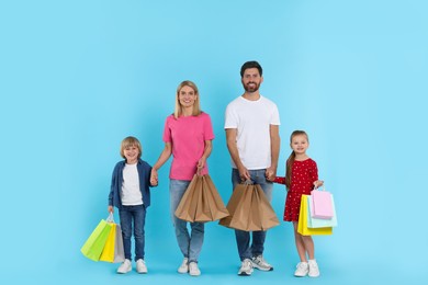 Photo of Family shopping. Happy parents and children with many colorful bags on light blue background